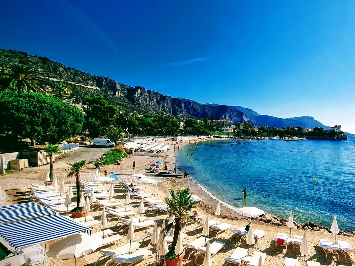 La plage de la baie des Fourmis à Beaulieu-sur-Mer, parasols et falaises