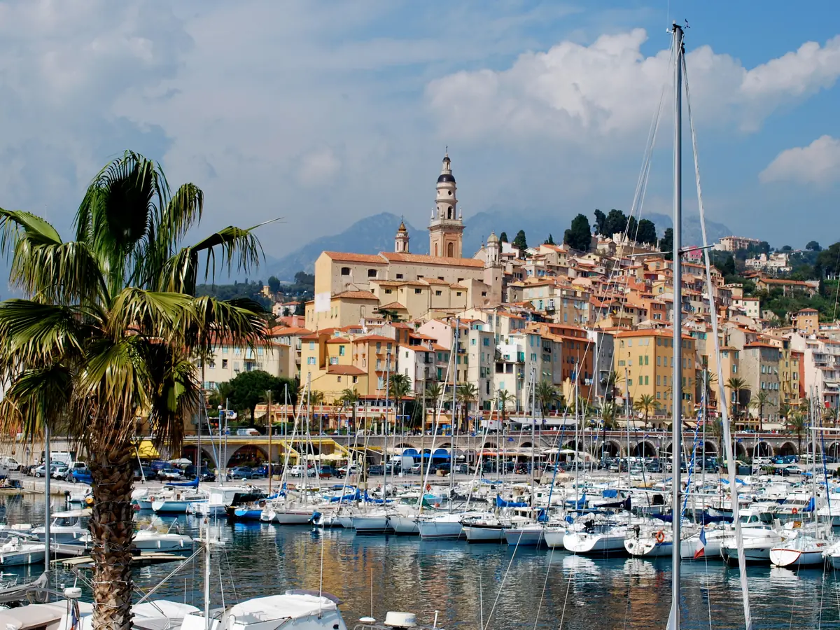 Le vieux port de Menton avec les bateaux devant la vieille ville et la basilique